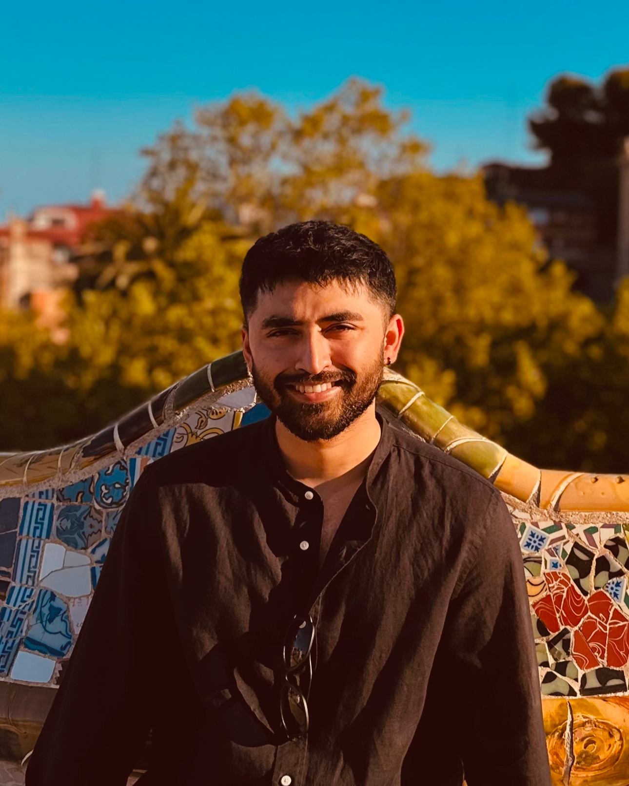 Man sitting on a colorful bench with trees and buildings in the background